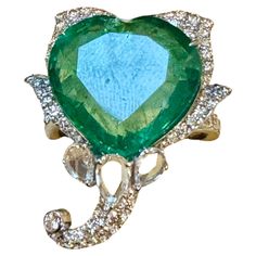 13 Ct Zambian Heart Cut Emerald & 1.5 Ct Diamond Ring, 18 Kt Gold Size 8.5 This classic ring features a Heart cut Zambian emerald of extreme fine quality, boasting a desirable color and luster, originating from Zambia. Accompanied by many rose cut diamonds , as well as brilliant cut diamonds totaling an approximate weight of 1.5 ct. The Pear & Marquise diamonds are artfully arranged as petals, creating a stunning display. 18 Karat white gold 7.8 gm. The rarity of fine emeralds adds to the allure of this exquisite piece. While it's challenging to fully capture the stone's true essence, professional and personal photos have been provided to showcase its beauty. As an Estate piece, all measurements and stone weights are approximate, reflecting the uniqueness of each item. Monalisajewelry Inc. Luxury Heart Cut Emerald Ring For Formal Occasions, Luxury Green Heart Cut Ring, 5 Ct Diamond Ring, Luxury Heart-shaped Gemstone Rings, Elegant Heart-shaped Emerald Ring, Luxury Heart-shaped Emerald Jewelry, Zambian Emerald, Marquise Diamond, Emerald Jewelry