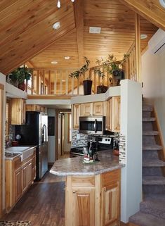 a kitchen with wooden cabinets and stairs leading up to the second floor