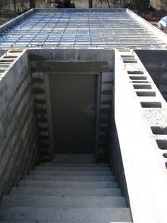 an open door is in the middle of a concrete wall with stairs leading up to it