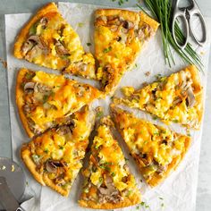 a pizza cut into eight slices on top of a white paper with green onions and mushrooms