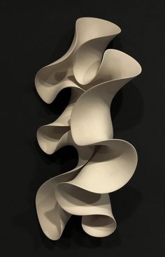 an abstract sculpture is displayed on a black surface with white lines in the form of wavy shapes