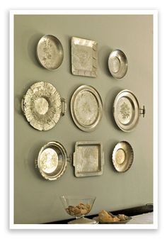 there are many silver plates on the wall and one has a glass plate in front of it