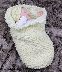 a baby wrapped up in a blanket on top of a furnishing floor,