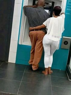 a man and woman standing in front of an atm machine with their backs to each other