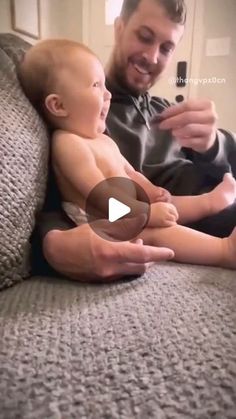 a man holding a baby on top of a couch