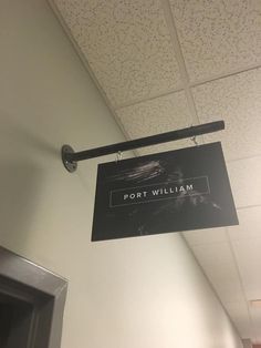 a black sign hanging from the ceiling in an office building that says port william on it