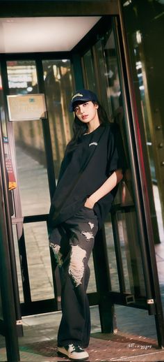 a woman standing in front of a glass door wearing ripped jeans and a black t - shirt