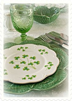 a plate with green shamrocks on it next to a glass and silverware set