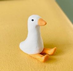 a white duck sitting on top of a yellow table