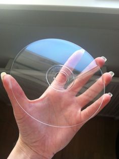 a person's hand is holding a clear disc