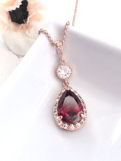 This necklace features a rose gold plated large peardrop halo dark red garnet cubic zirconia, surrounds with little multi round cubic zirconia gems, with a round cubic zirconia  with a CZ bail,  in a beautiful white gold plated tarnish resistant chain. (normal cable chain is also available, please let me konw if you prefer the cable chain). Size: Pendant : 15 x 33 mm , or 1.3 inches long, and 15 x 29 with the bail Chain: 16 inches with 2 inches extension Matching Earrings: https://www.etsy.com/au/listing/250724980/bridal-earring-rose-gold-long-large-red **NOTE: CUBIC ZIRCONIA HAS MANY DIFFERENT GRADES, AND ALL THE CUBIC ZIRCONIA USED IN MY DESIGN IS OF THE HIGHTEST QUALITY. IT SPARKS LIKE DIAMOND AND MUCH PRETTIER IN PERSON)  **Express Shipping available, delivery in about 3 business days Necklace Rose Gold, Cz Necklace, Necklace Rose, Bridal Necklace, Rose Gold Necklace, Red Garnet, Bridesmaid Jewelry, Bridal Earrings, Matching Earrings