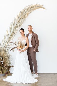 a bride and groom standing next to a palm tree