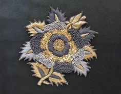 a close up of a flower on a black cloth with gold and silver sequins