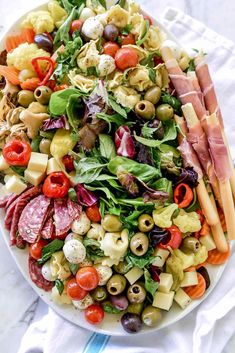 a large salad on a white plate topped with meats and vegtables