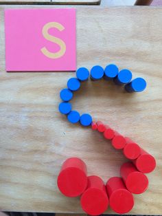 the letter s is made out of red and blue plastic circles on a wooden table