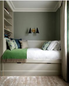 a bedroom with green and white decor on the walls, carpeted flooring and built in bookshelves