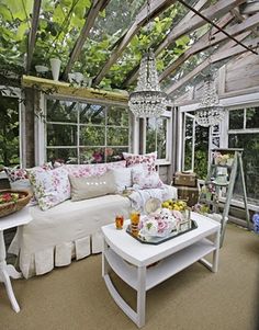 a living room filled with furniture and lots of windows covered in greenery next to a white couch