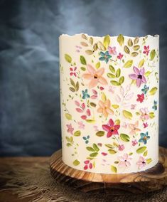 a cake decorated with flowers and leaves on a wooden stand