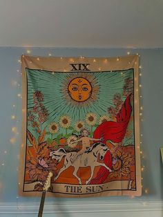 a tapestry hanging on the wall above a clock in a room with blue walls and string lights