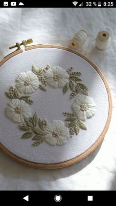 an embroidery project with white flowers and green leaves