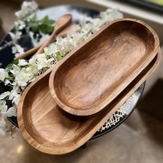 two wooden spoons sitting on top of a plate next to white and green flowers