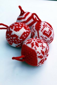 three red and white knitted ornaments sitting on top of a table