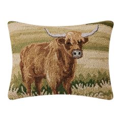 an embroidered pillow with a brown cow on it's side and grass in the background