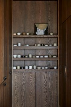 a wooden shelf filled with bowls and cups