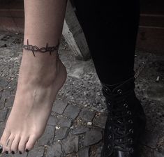 a person with a tattoo on their foot standing next to a brick wall and holding an umbrella