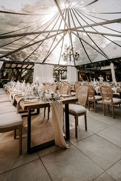 the inside of a tent with tables and chairs set up for a formal dinner or party