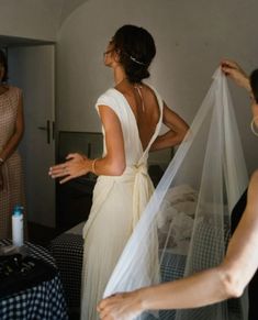 the bride is getting ready to go into her wedding dress with her veil pulled back