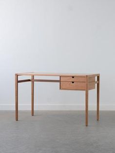 a wooden desk with two drawers on the top and one drawer at the bottom, in front of a white wall