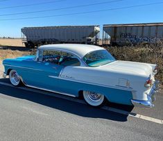 an old blue and white car parked on the side of the road