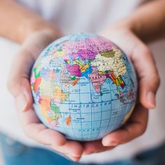 a person holding a small globe in their hands with both hands on top of it