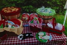 there are many baskets and plates on the picnic table with red checkered cloths