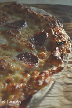 a pizza sitting on top of a wooden cutting board covered in cheese and pepperoni