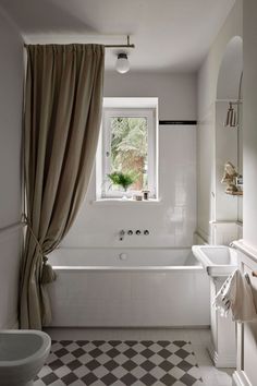 a bathroom with a checkered floor, tub and window in the middle of it