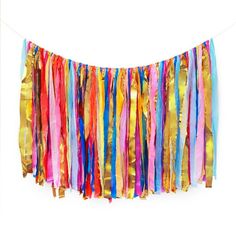 colorful streamers hanging from a string on a white wall in front of a white background