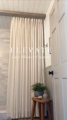 a white curtain hanging from the side of a wall next to a small table with a potted plant on it