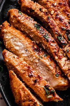 sliced pork chops in a cast iron skillet with herbs and seasoning on top