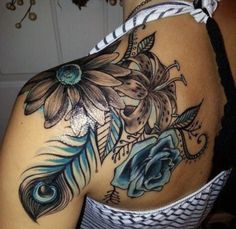 the back of a woman's shoulder with blue flowers and peacock feathers on it