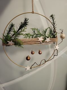 a circular hanging decoration with ornaments and greenery on the top is hung from a rope