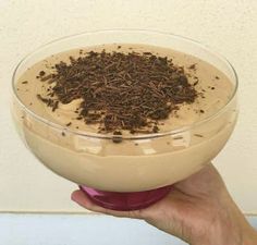 a hand holding a bowl filled with chocolate and powdered coffee flakes on top of it