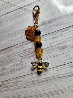 a yellow and black beaded keychain with a bee charm hanging from it's side