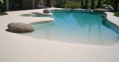 an outdoor pool with rocks and grass around it