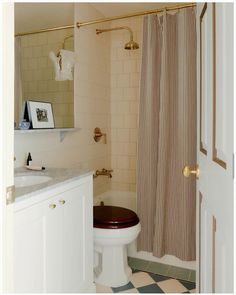 a white toilet sitting next to a shower curtain in a bathroom with black and white checkered flooring