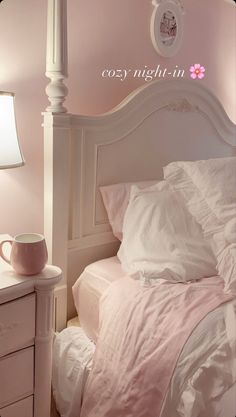 a white bed sitting next to a night stand with a cup on top of it