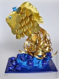 a gold fish made out of coins on top of a blue plate with candy in it