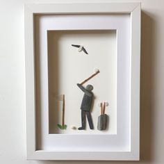 a shadow of a man holding a baseball bat and standing next to a bird in a white frame