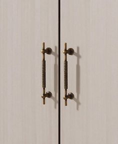 two white cupboards with brass handles and knobs on each door, one is closed